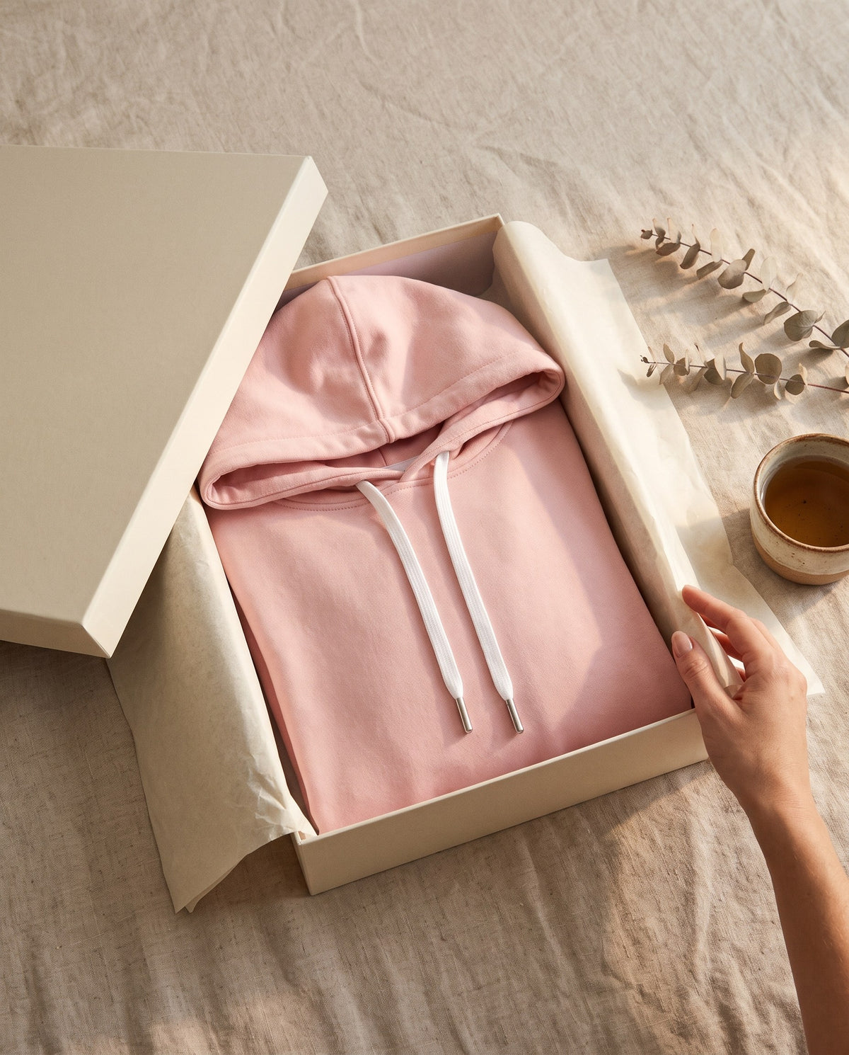 Blush pink Junemae hoodie dress folded in an ivory box with tissue paper