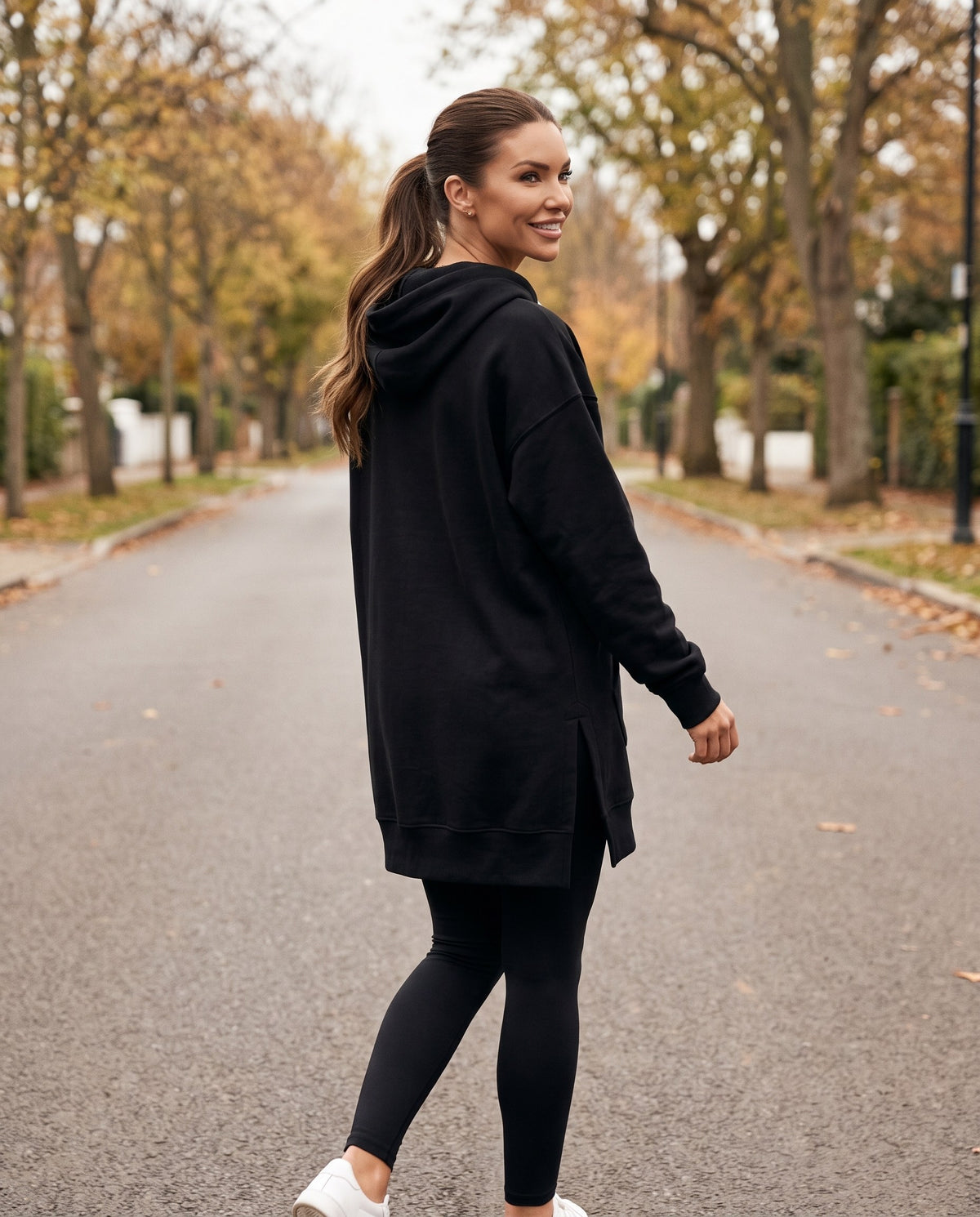 Back view of the black hoodie dress showing the mid-thigh length over leggings