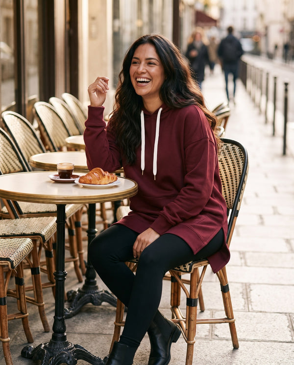 Burgundy hoodie dress styled with black leggings and ankle boots at a cafe
