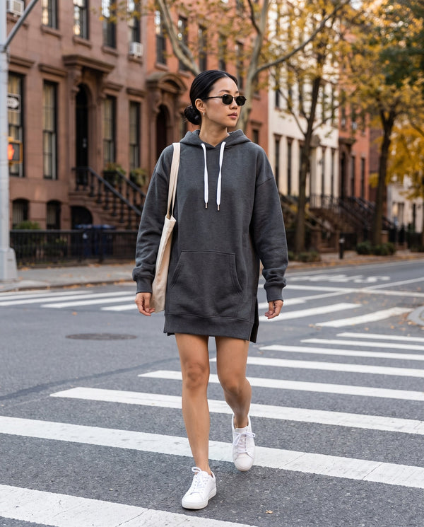 Charcoal oversized hoodie dress styled with white sneakers and a tote in the city