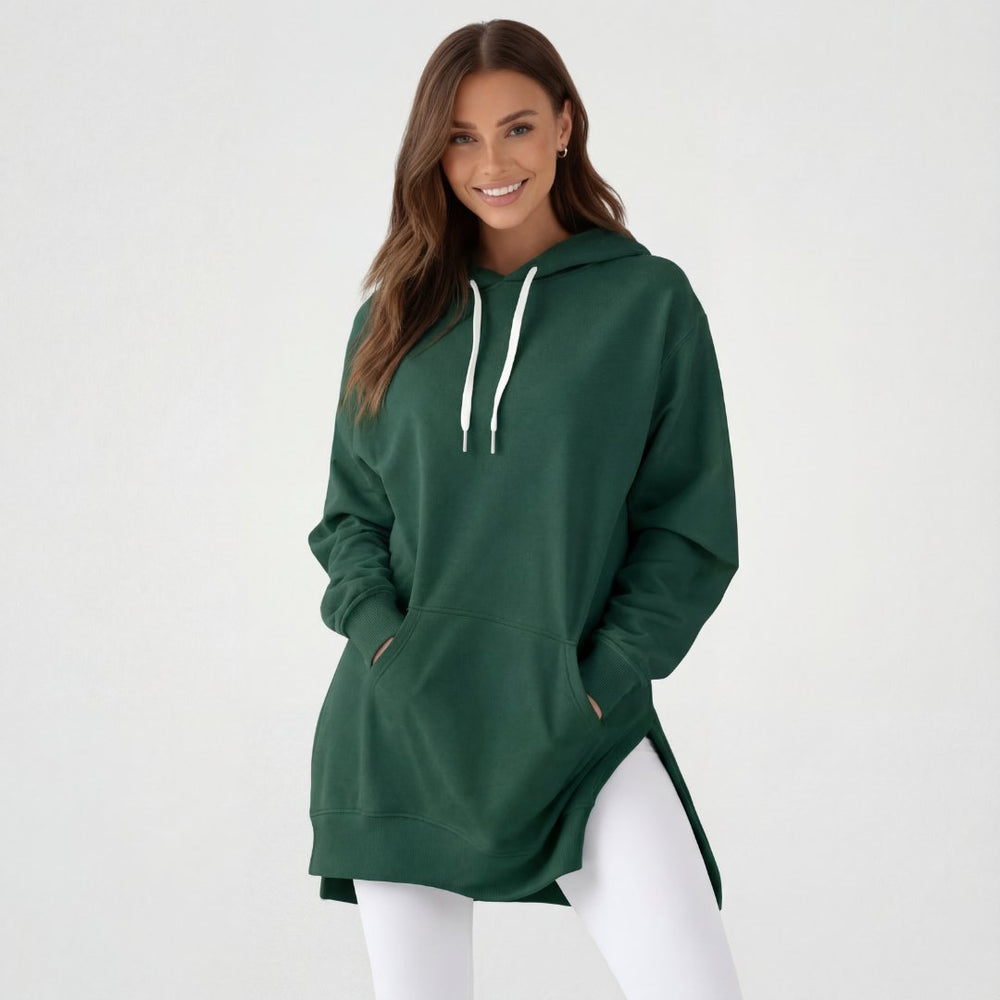 Woman wearing the Junemae oversized hoodie dress in forest green, with side slits and a kangaroo pocket
