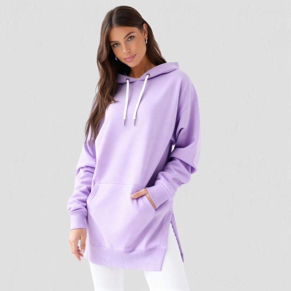 Woman wearing the Junemae oversized hoodie dress in lavender, with side slits and a kangaroo pocket