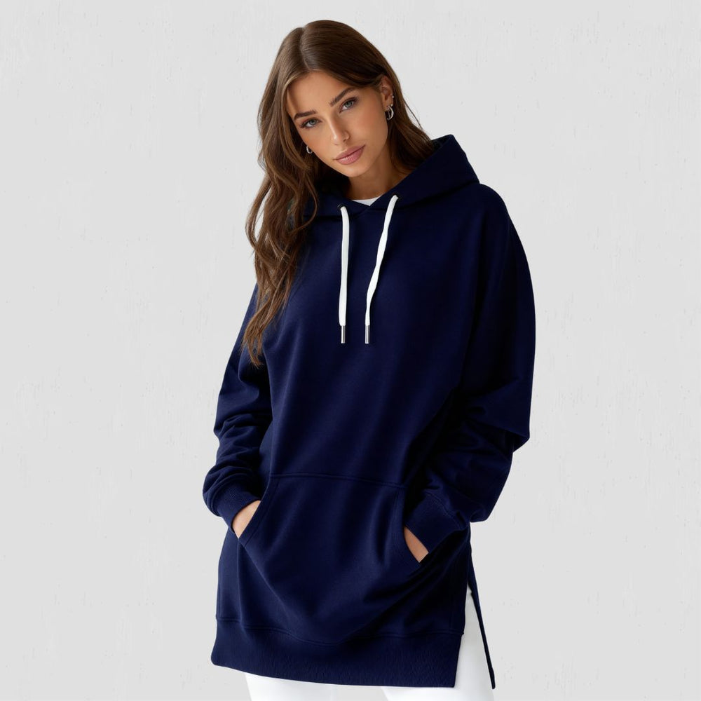 Woman wearing the Junemae oversized hoodie dress in navy, with side slits and a kangaroo pocket